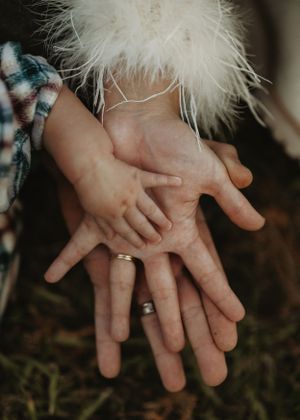 Close up of overlapping hands with wedding rings showing family connection.