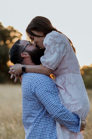 Intimate romantic moment captured during a golden hour photoshoot in a field.