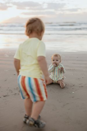 Two young children playing on a beach at sunset.