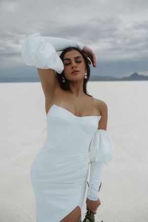 A dramatic bridal portrait on salt flats featuring an off-shoulder white gown.