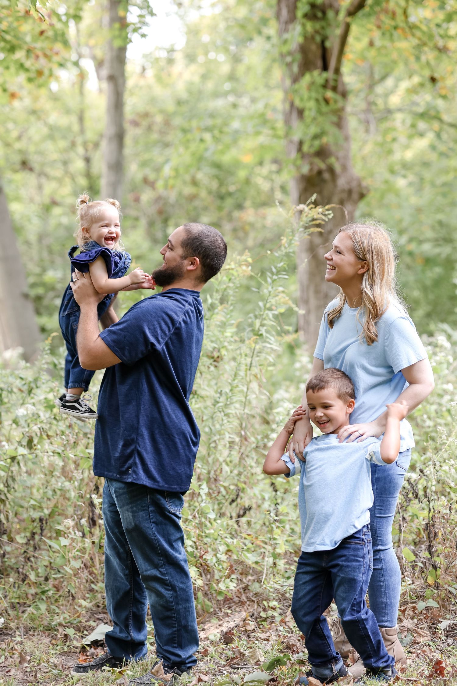 A happy family sharing joyful moments together in a wooded outdoor setting during a sunny day.