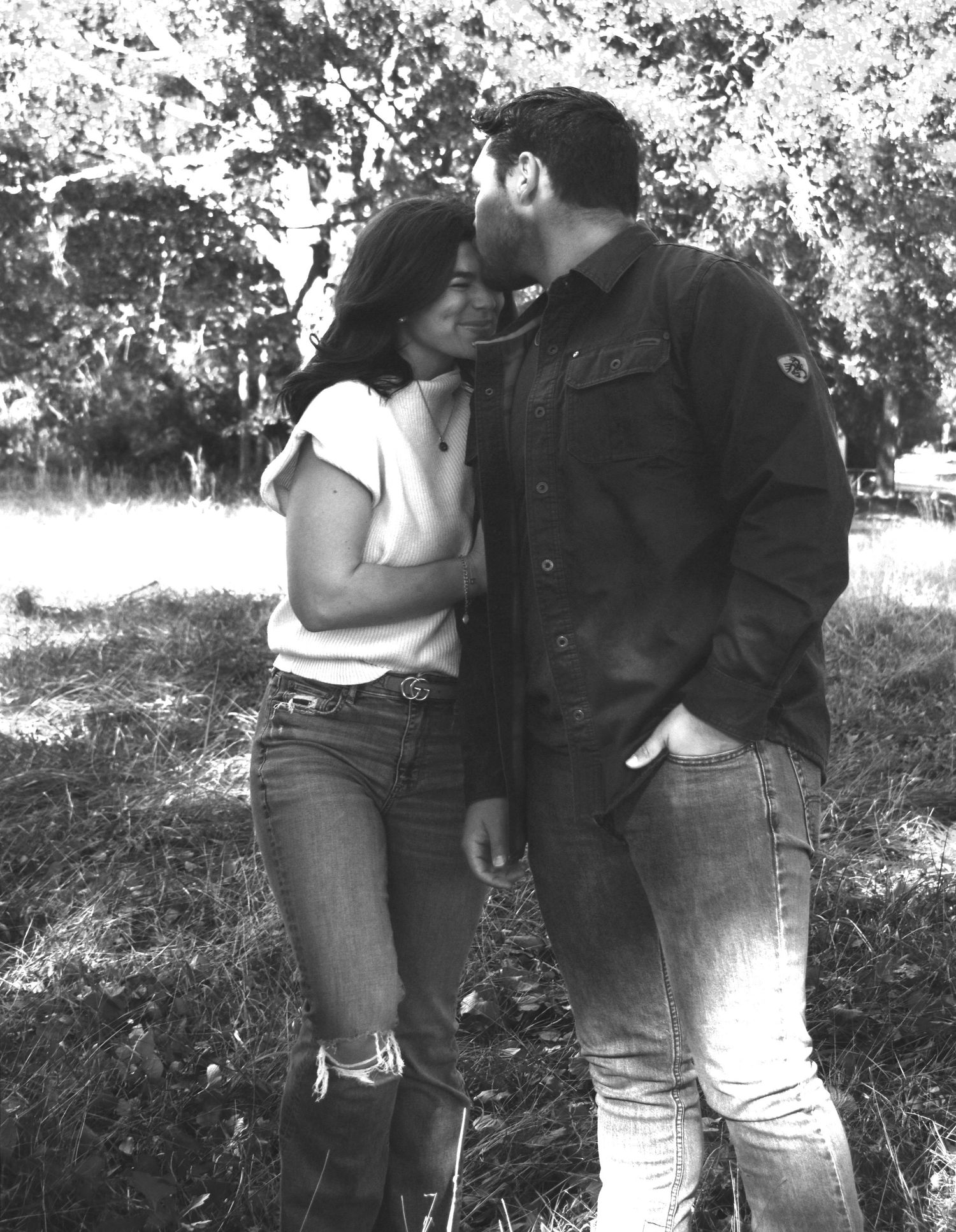 Black and white photo of intimate couple moment outdoors in casual attire.