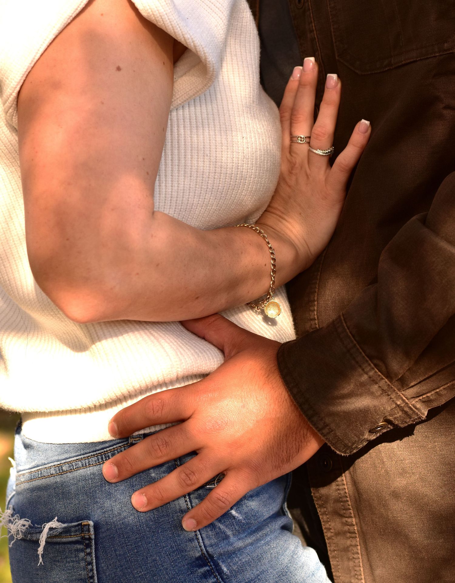 Close-up shot of hands touching with white sweater and jeans against dark background.