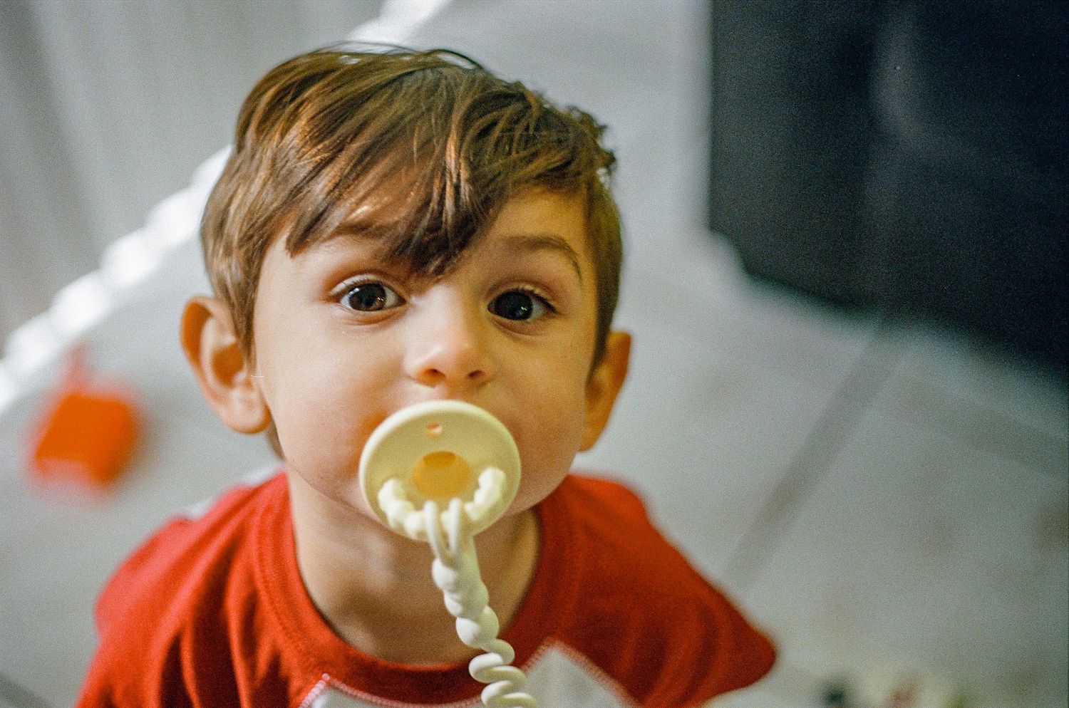 Child drinking from a clear straw against white background.