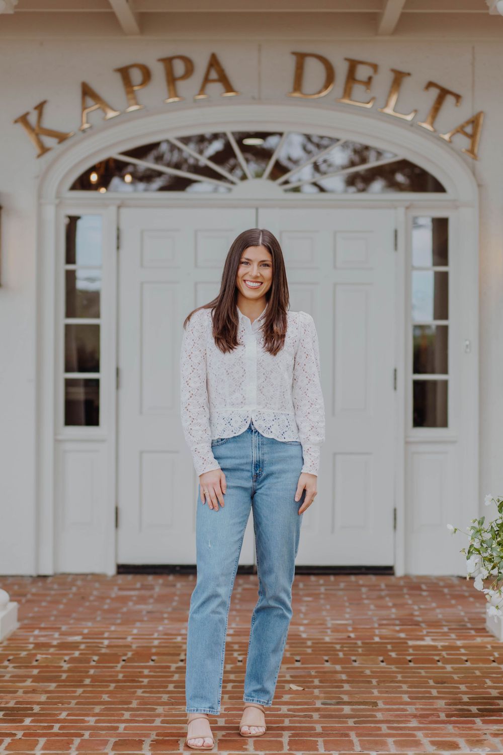 Student poses in front of Kappa Delta sorority house entrance wearing casual attire.