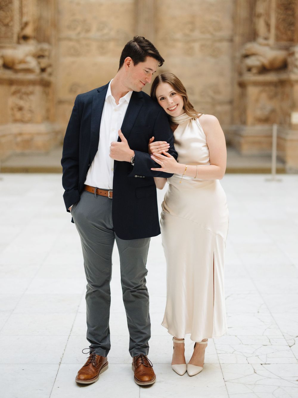 Stylish couple sharing a laugh against historic stone architecture.