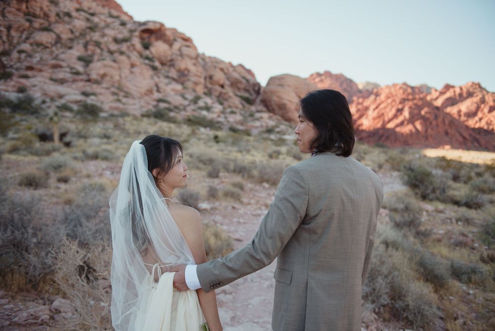A bride and groom are walking together at red rock canyon in Las Vegas.