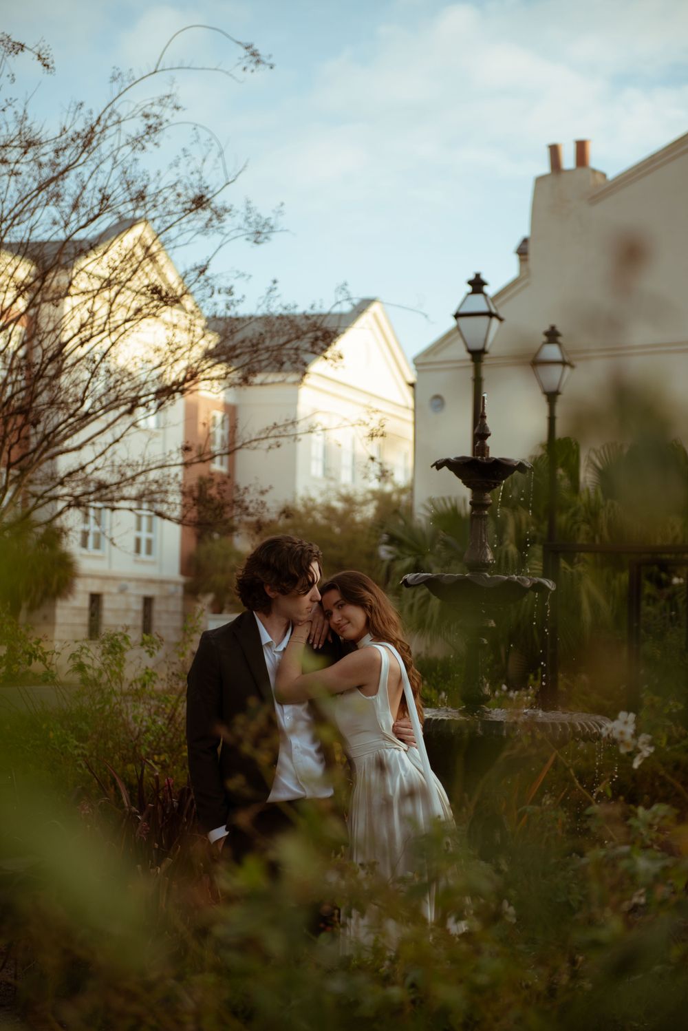 A bride and groom are embracing each other in a park in downtown Charleston, South Carolina.