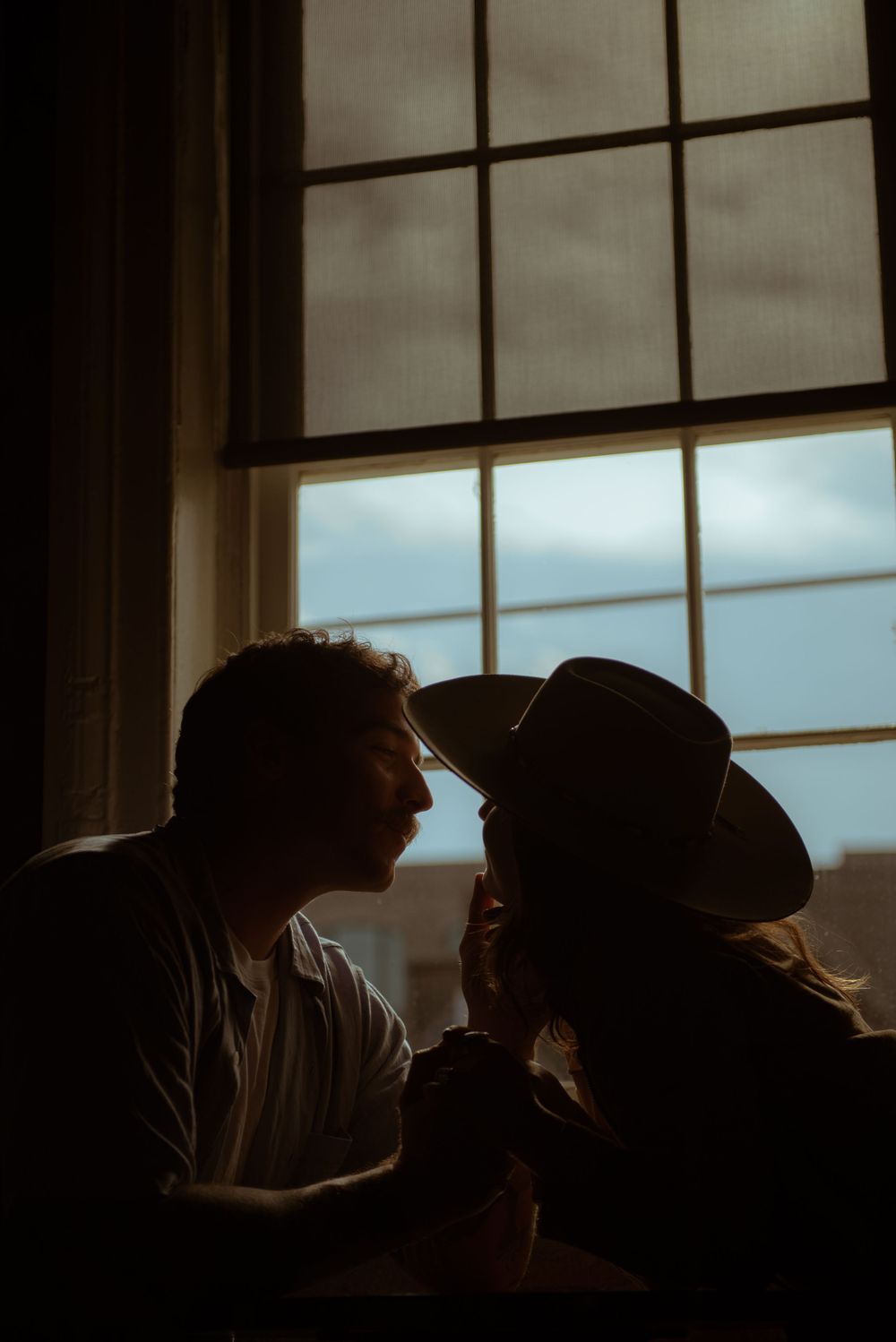A couple are gazing into each others eyes while the girl is wearing a cowgirl hat.