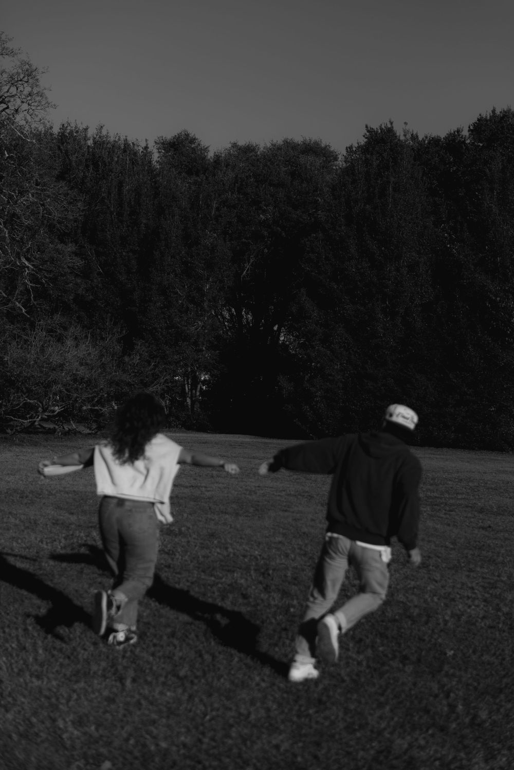 A black and white photo of a couple holding hands and running together in a field in Charleston, South Carolina.