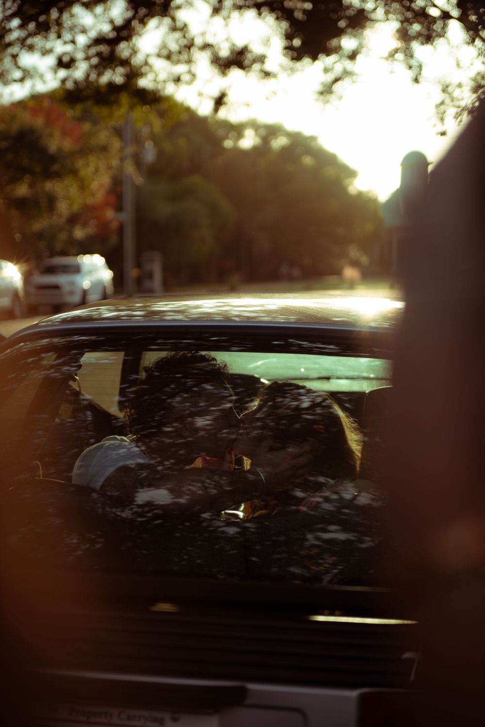 A couple are kissing inside a vintage car.