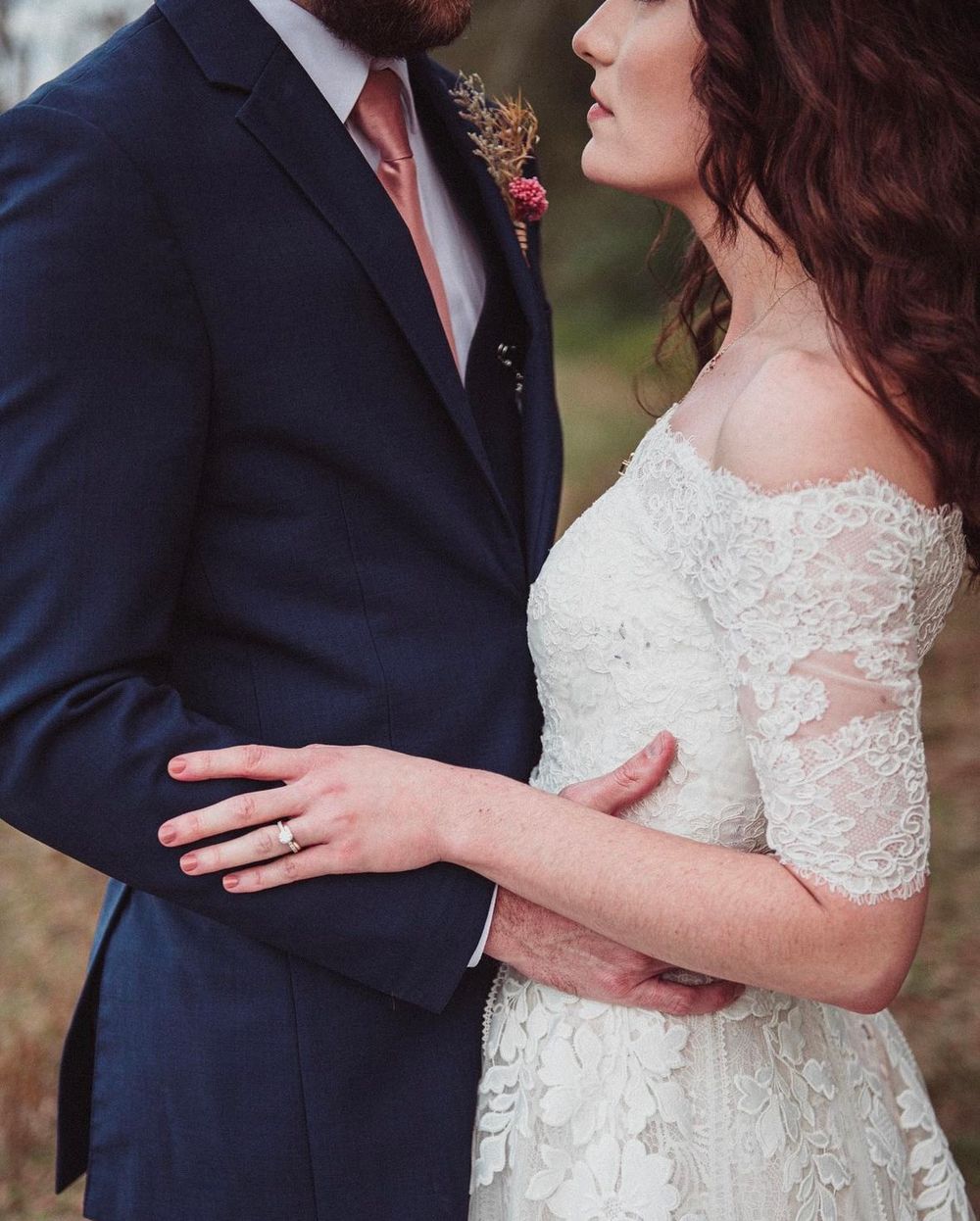 A bridge and groom are embracing one another face to face.