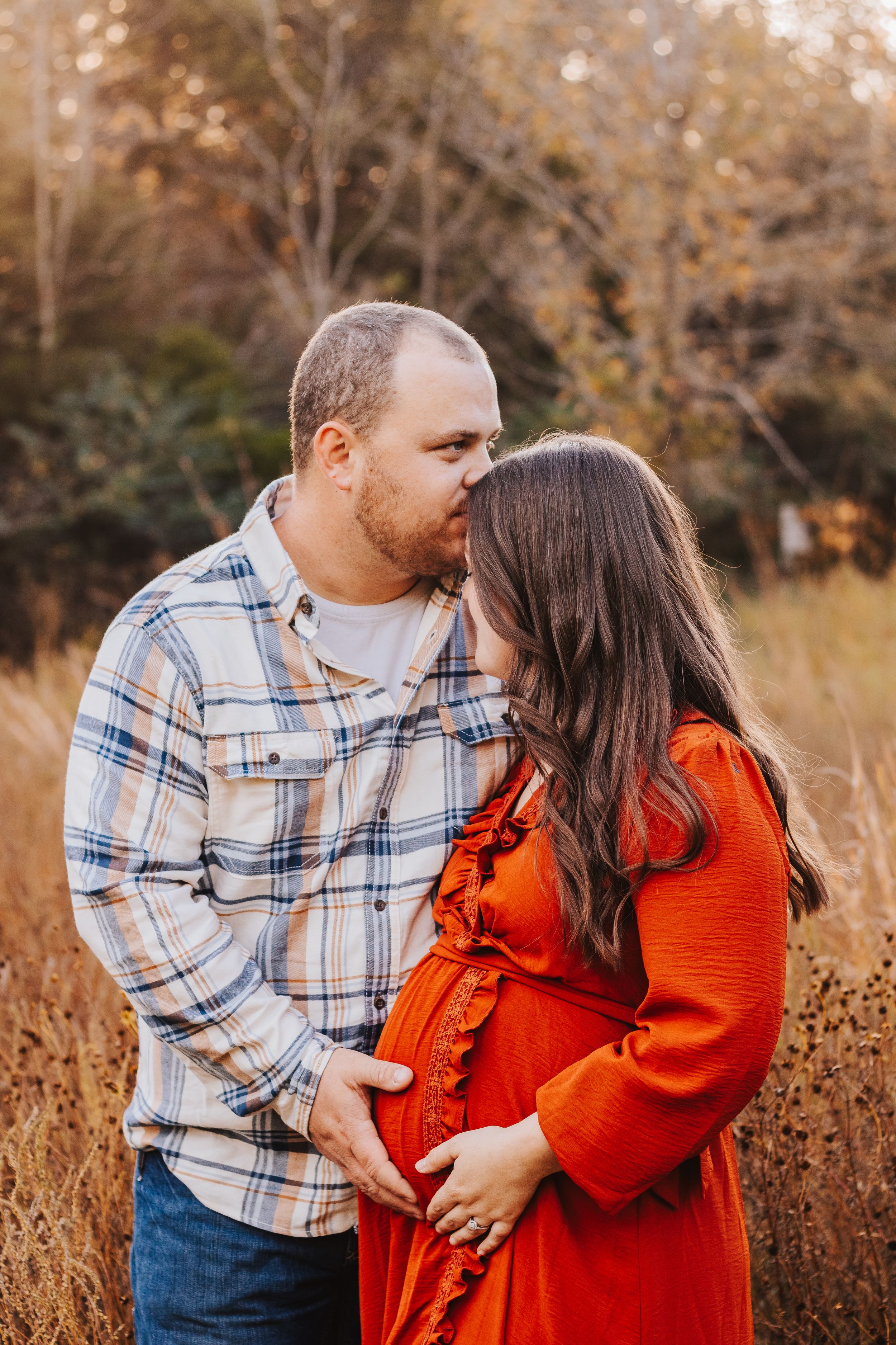 Romantic couple shares tender moment in autumn field at golden hour.