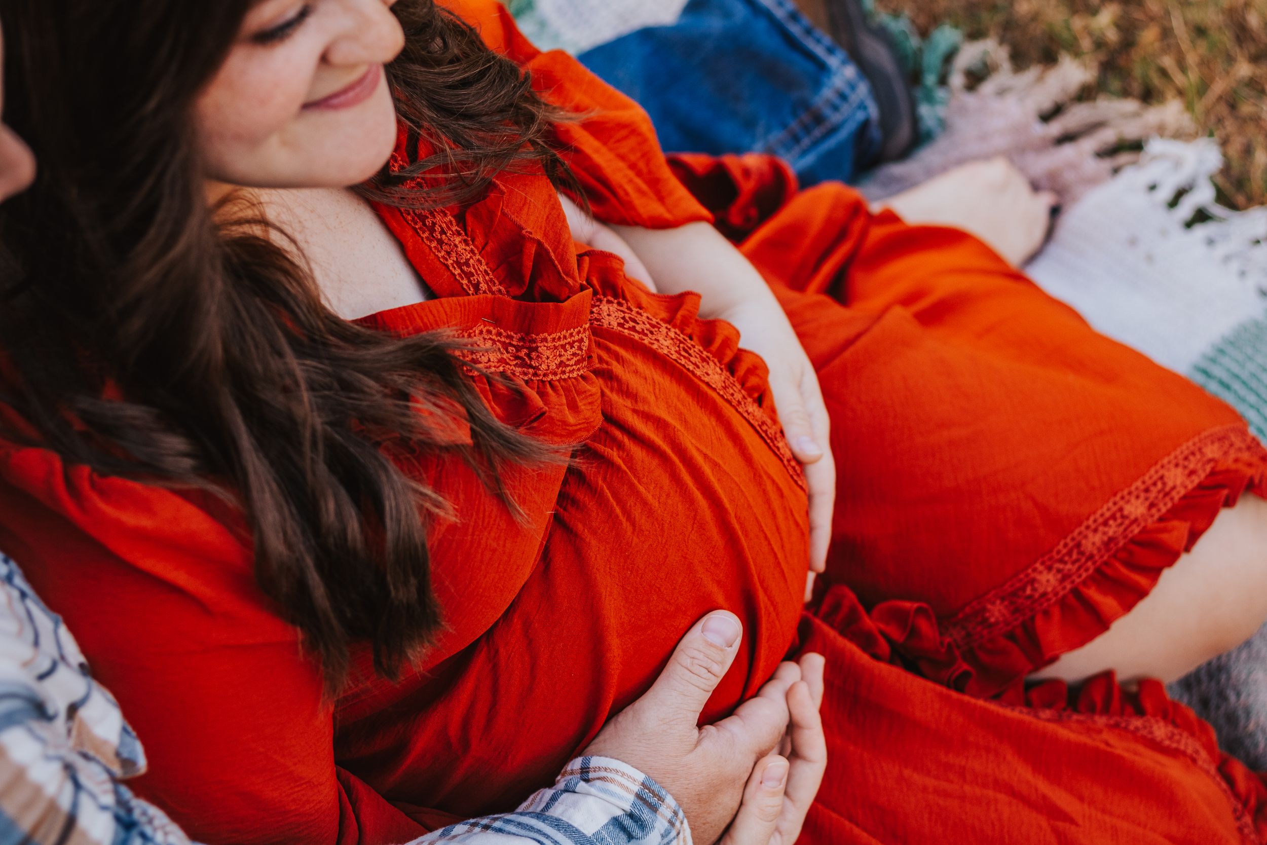 Detail shots of maternity moments in vibrant orange dress against fall backdrop.