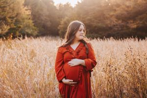 Golden hour maternity photography in autumn field with warm lighting.