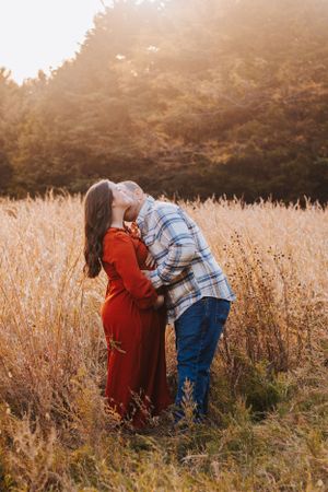 A romantic couple shares tender moments in a golden wheat field at sunset.