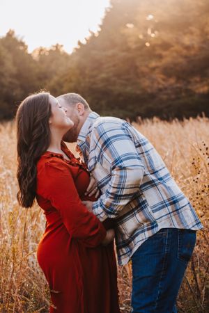 A couple embraces lovingly among tall grass during golden hour photography session.
