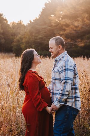 Two people share playful interactions in a sunlit field with tall grass.