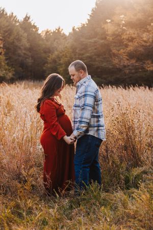 Couple shares intimate moments in autumn field during sunset photoshoot.