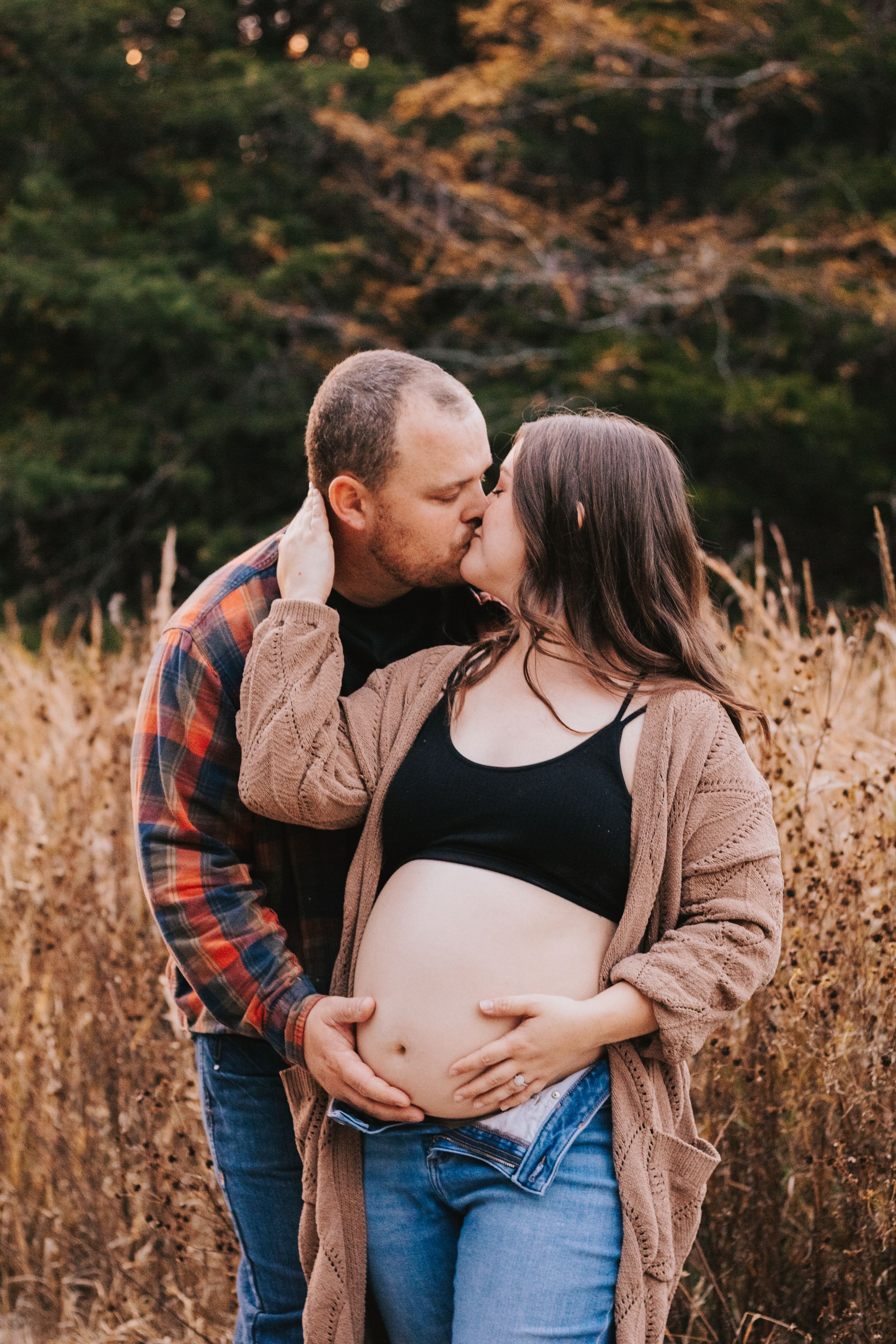 Beautiful outdoor maternity session featuring couple in casual attire against fall landscape.