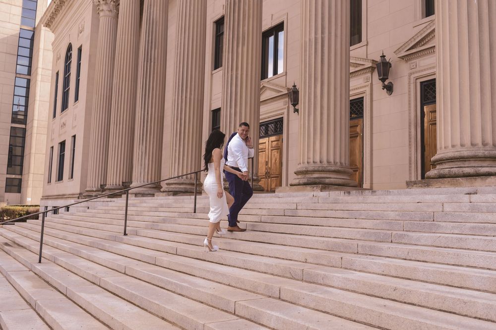 Engaged couple walking up the stairs right outside of Mecklenburg Courthouse in Charlotte, North Carolina