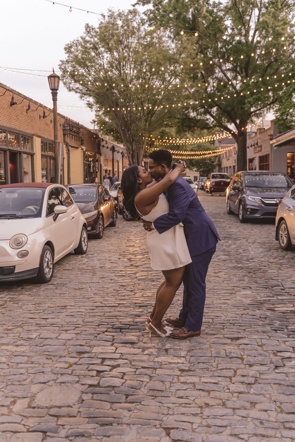 Engaged couple kissing on cobble stone streets in downtown Raleigh, North Carolina