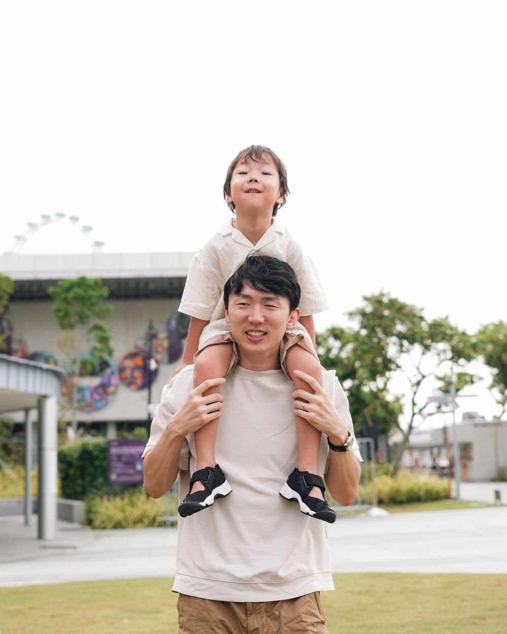 Child riding on shoulders while enjoying outdoor playtime in Singapore.