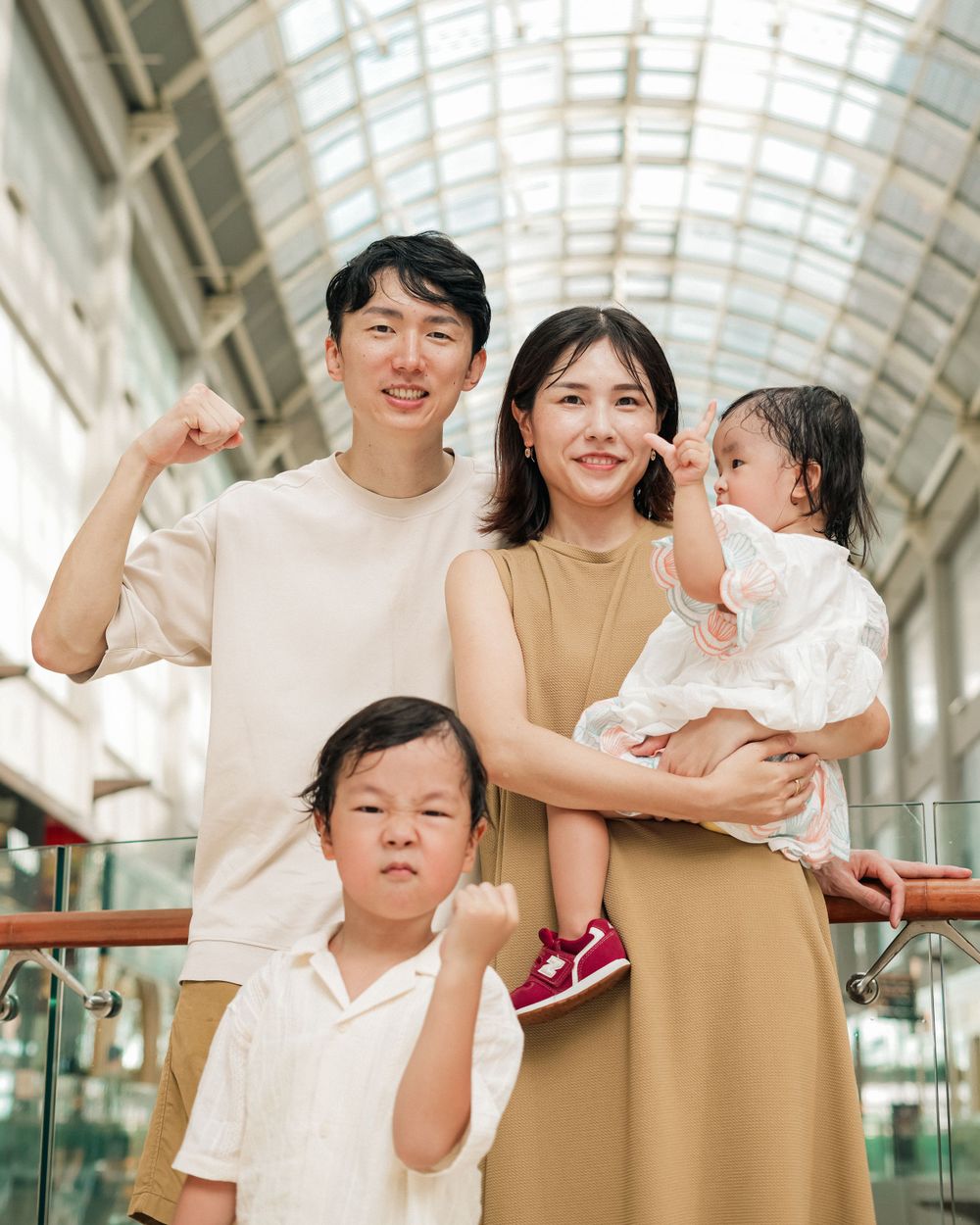 A family poses together in a bright indoor mall setting.