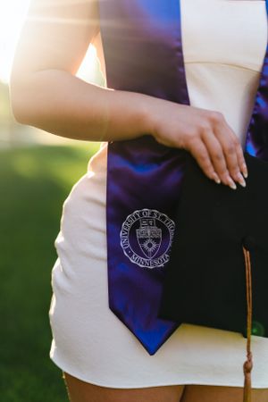 Close-up of graduation stole with university seal in evening light.