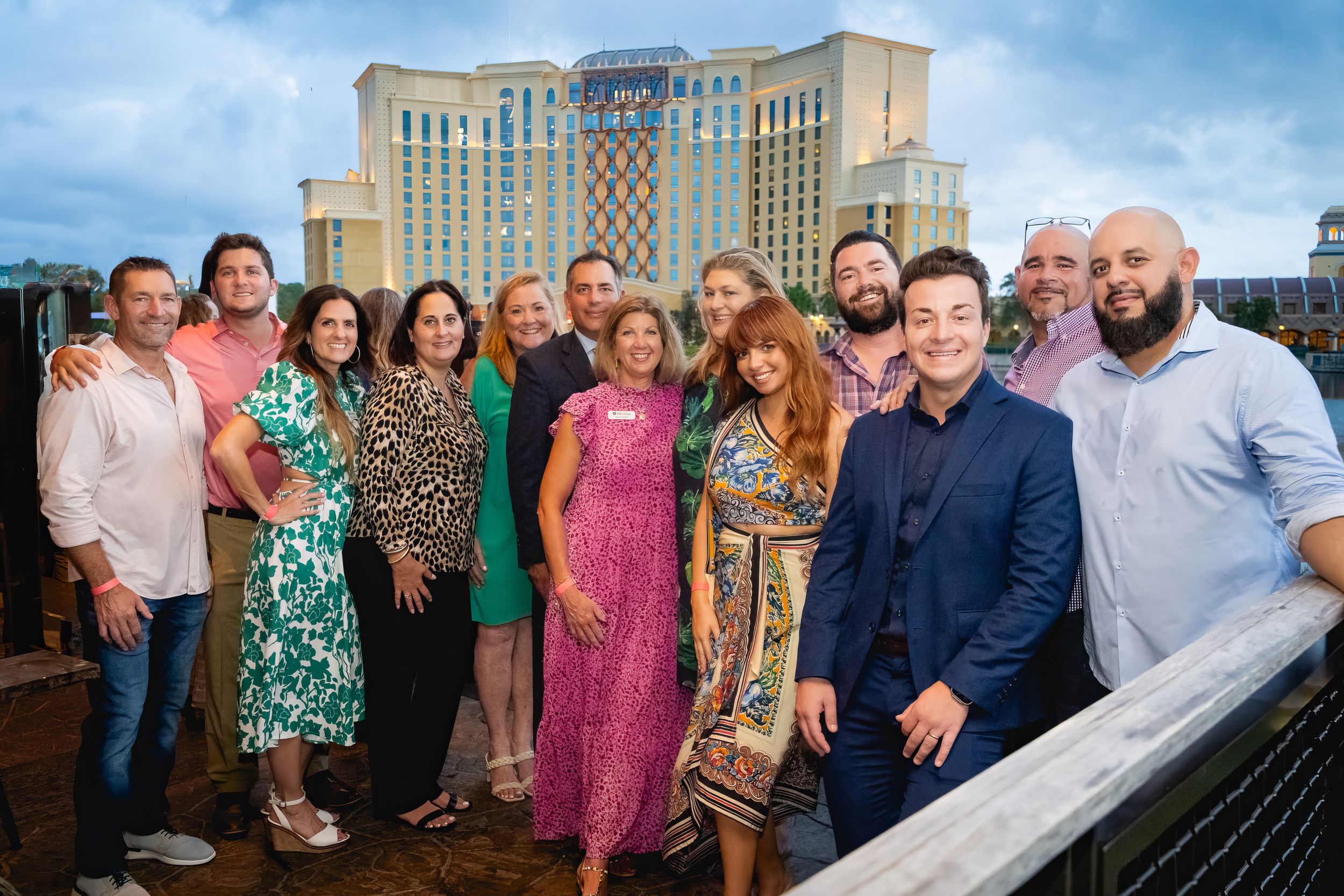 A group of people posing together on a rooftop with a large hotel or casino building visible in the background.