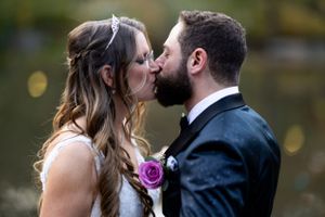 A romantic wedding kiss moment captured in an outdoor garden setting.
