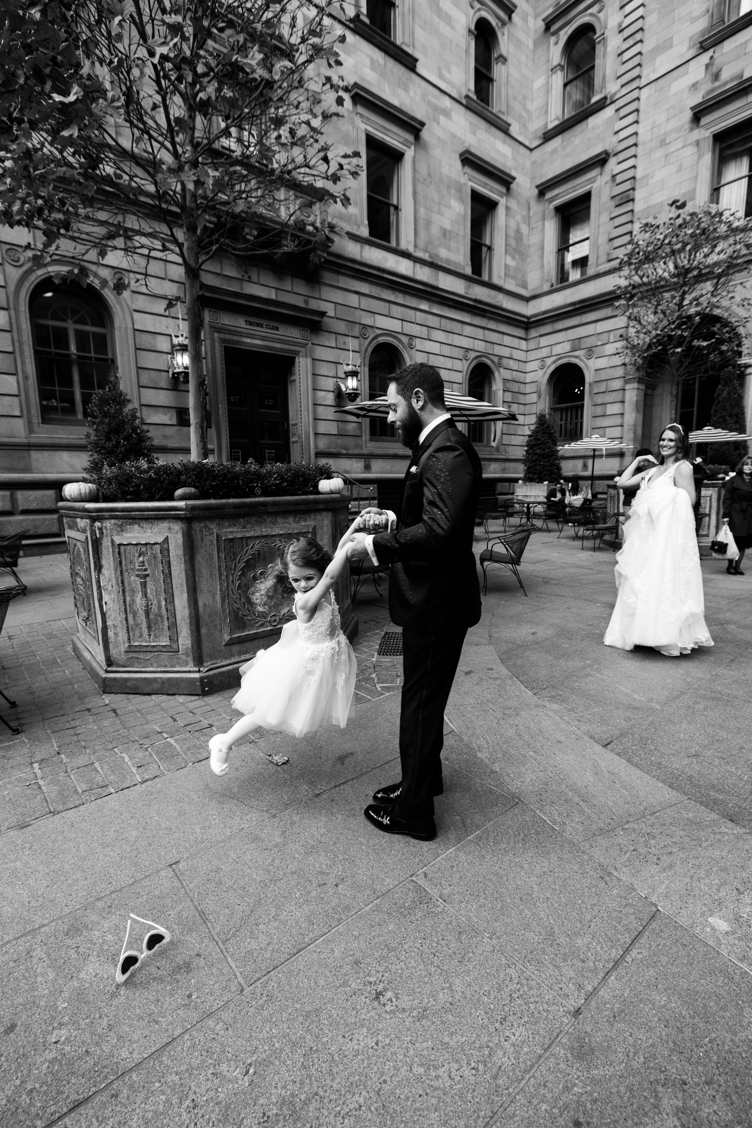 Black and white candid moment of wedding party in courtyard.