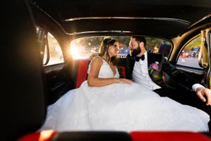 A candid wedding moment inside a taxi cab with formal attire.