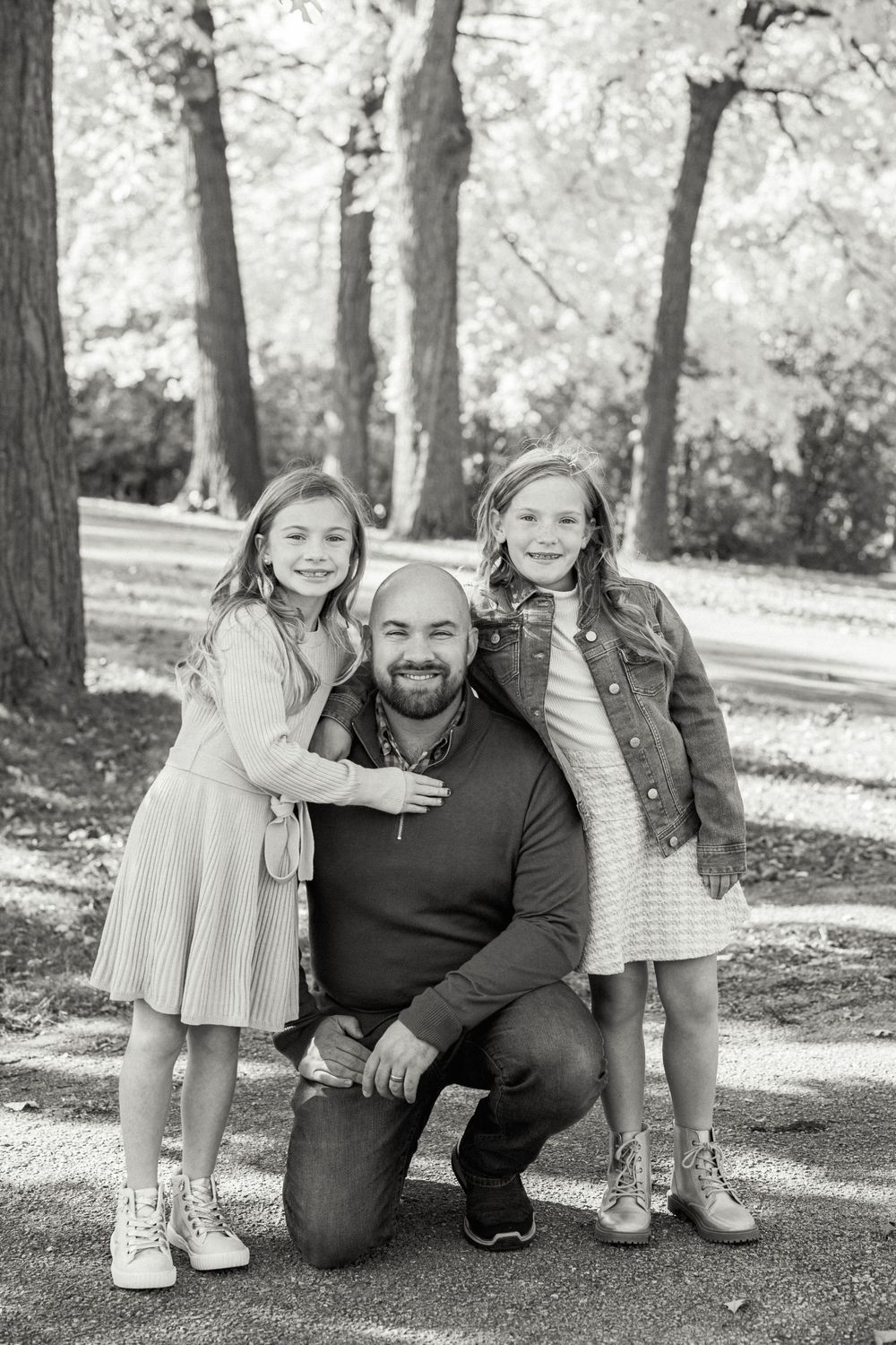 A candid family moment captured in black and white under autumn trees.