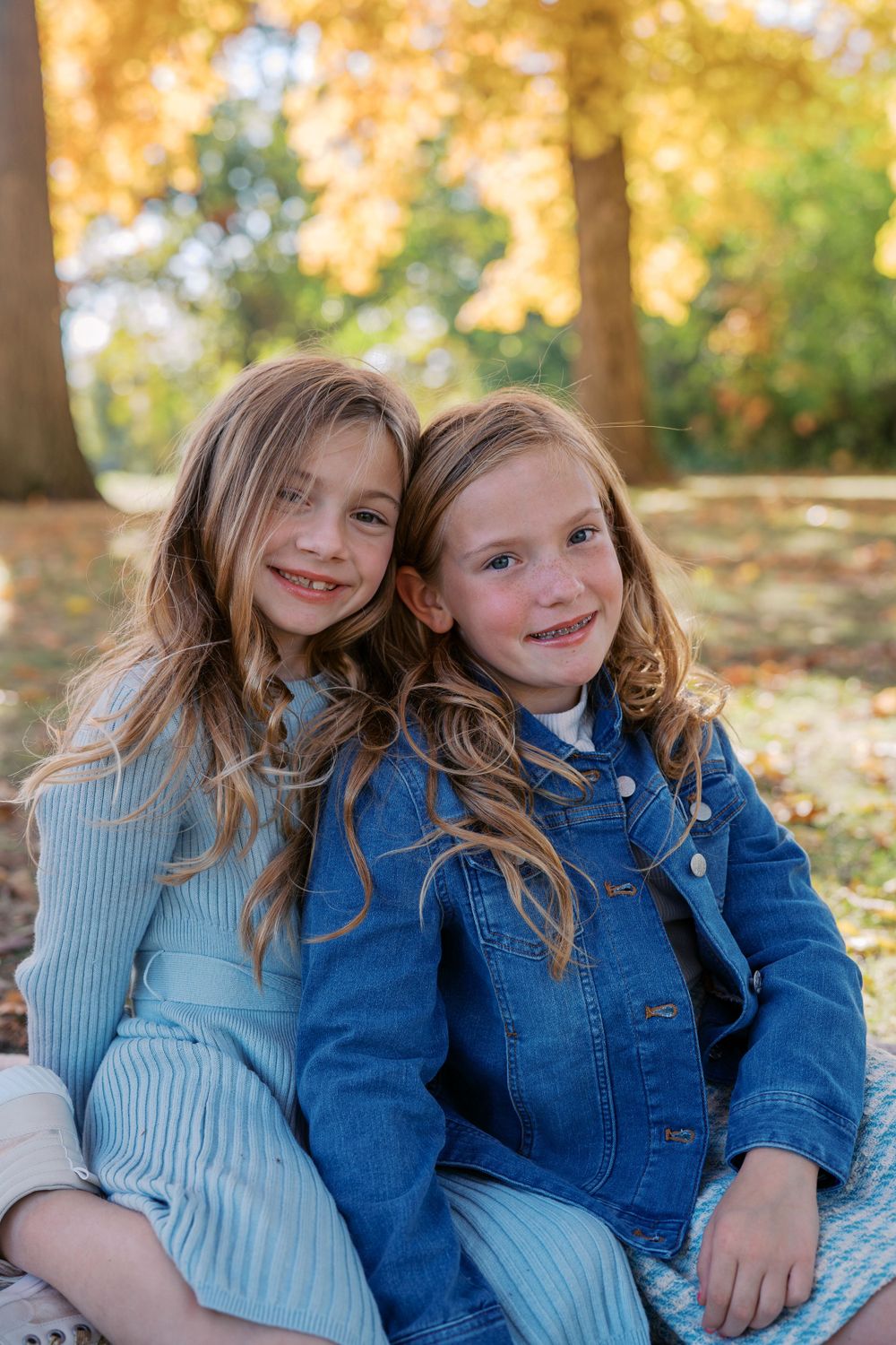 Two children in blue outfits share a sweet moment during a fall photo session.