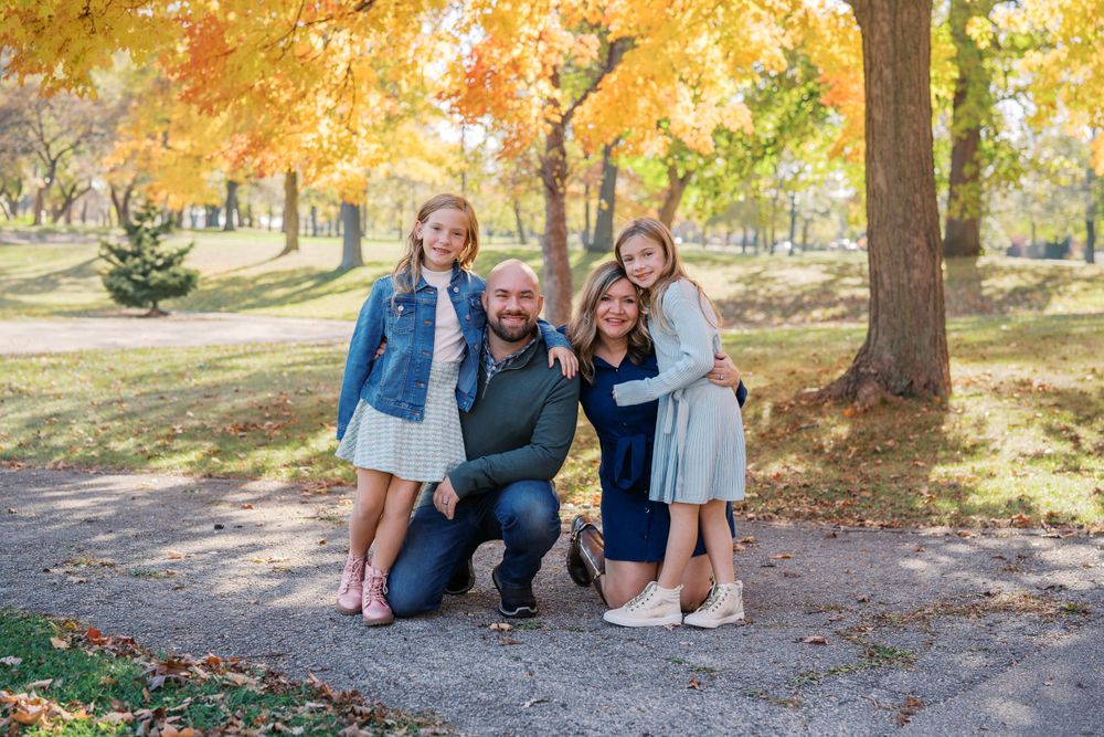 Family group photo taken on path surrounded by golden autumn trees.