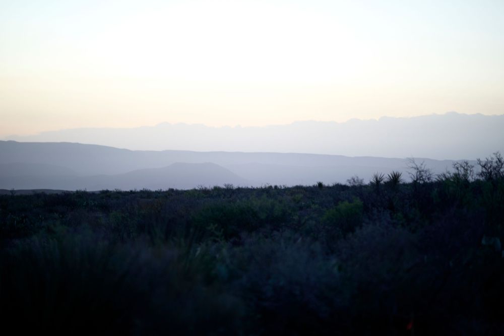 Silhouette of mountain ranges and trees during twilight creating a layered landscape effect.