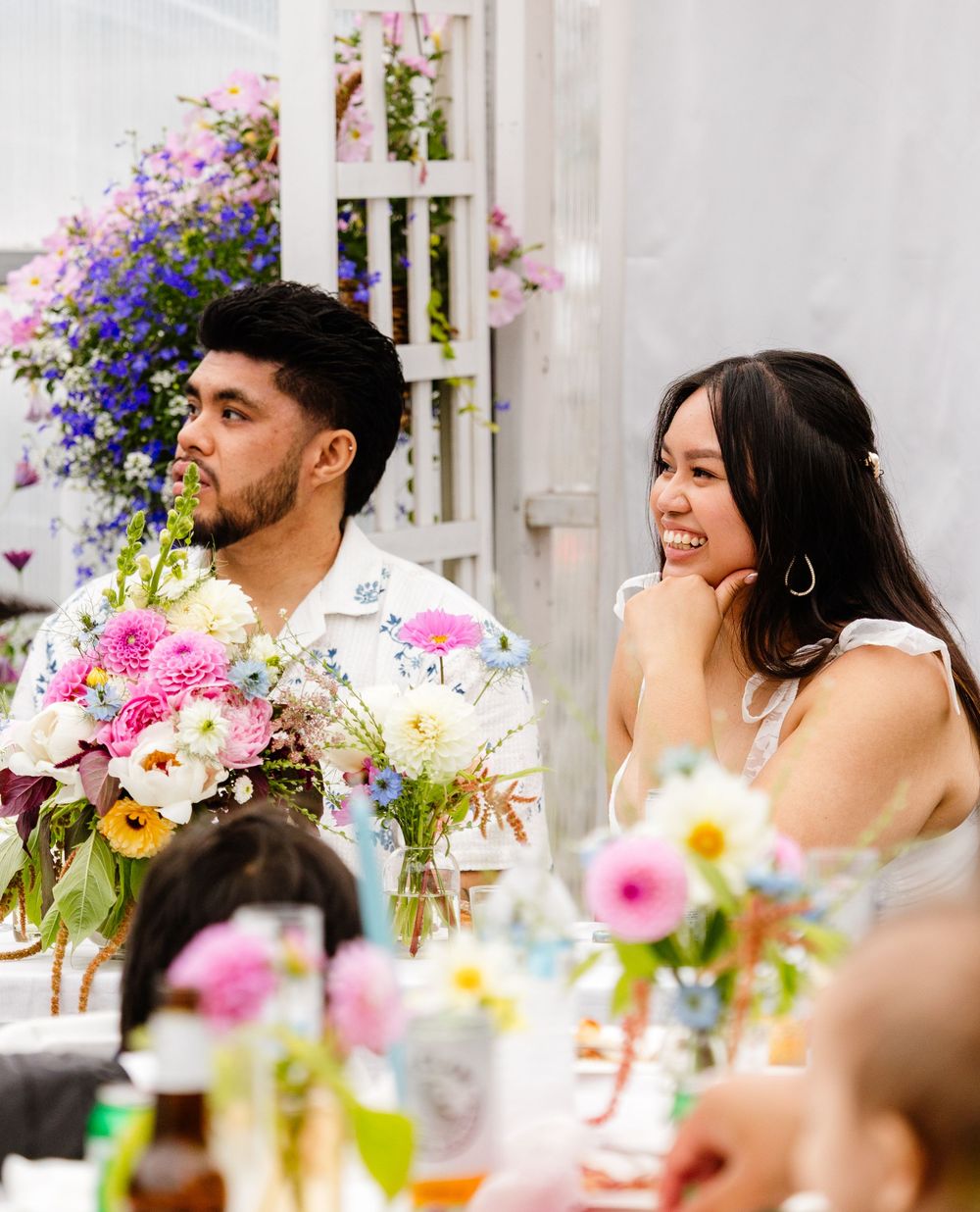 A group enjoys an outdoor dinner gathering with colorful floral arrangements and festive table settings.