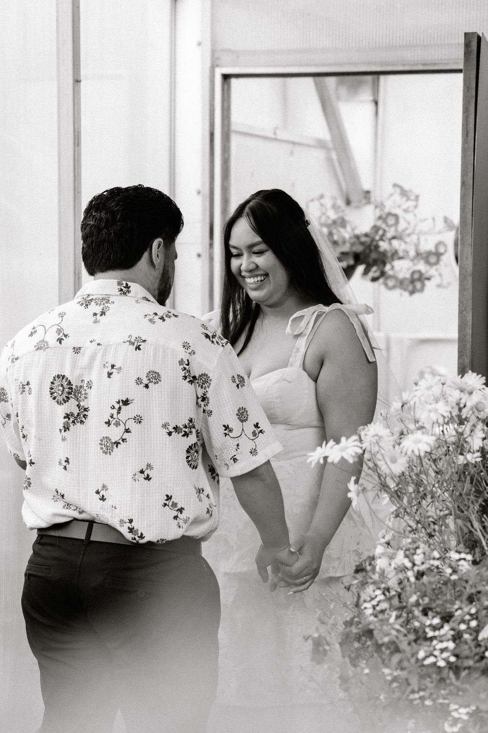 A black and white photo of a couple in a garden setting sharing a joyful moment together during their photoshoot.