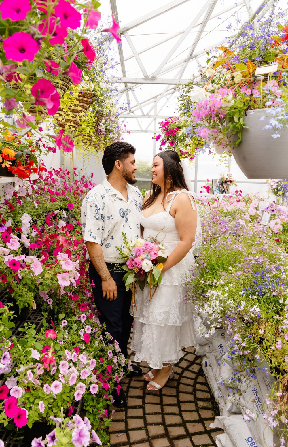 A romantic moment surrounded by vibrant blooming flowers in a greenhouse greenhouse with pink, purple and white petals.