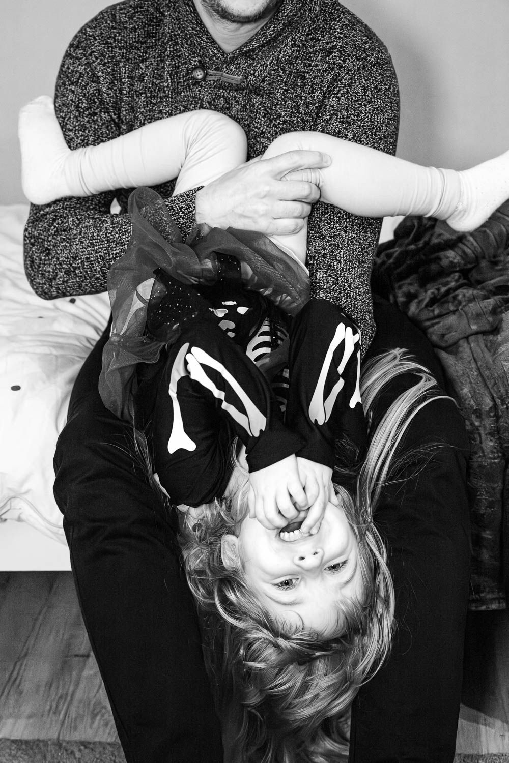 Photo pleine de complicité, papa et enfant riant aux éclats pendant un jeu lors d'une séance photo famille dans la Loire