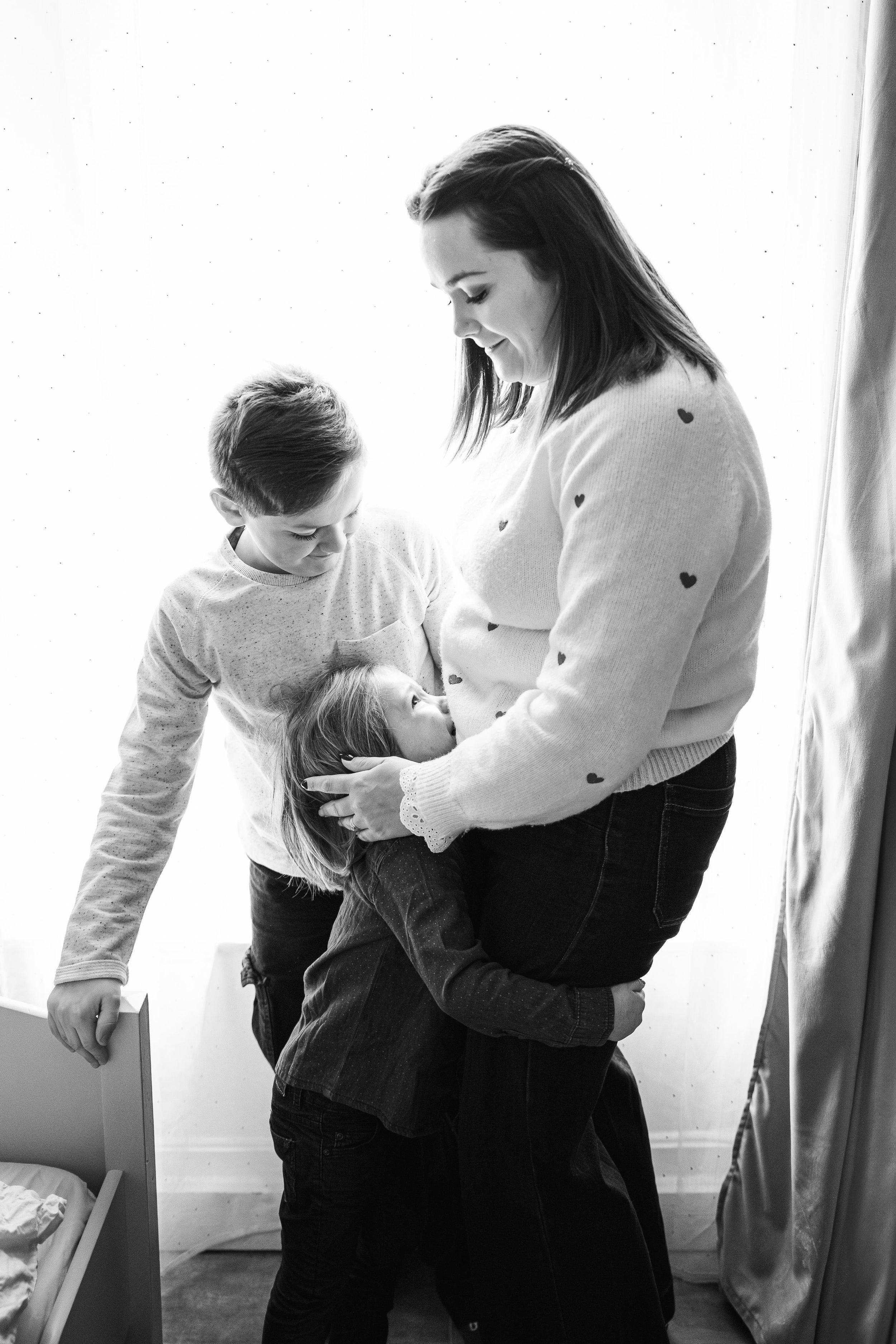 Photo touchante d'une mère serrant ses enfants dans ses bras, séance lifestyle à domicile dans la Loire