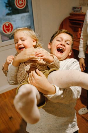 Enfants jouant ensemble dans une chambre, scène du quotidien pleine de spontanéité en séance photo famille près de Saint-Étienne