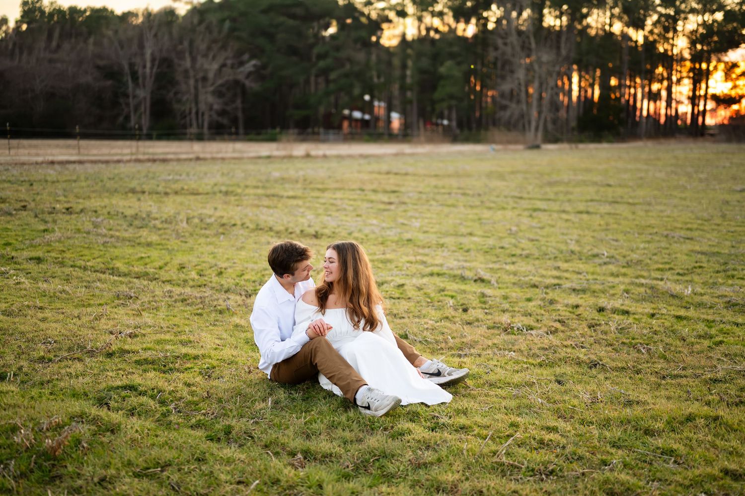 A romantic black and white maternity photo of an expecting couple embracing on a wooden dock by the water.