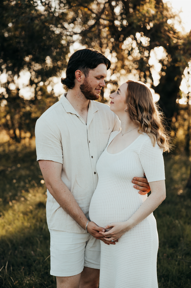 Romantic maternity photoshoot at golden hour in white outfits.
