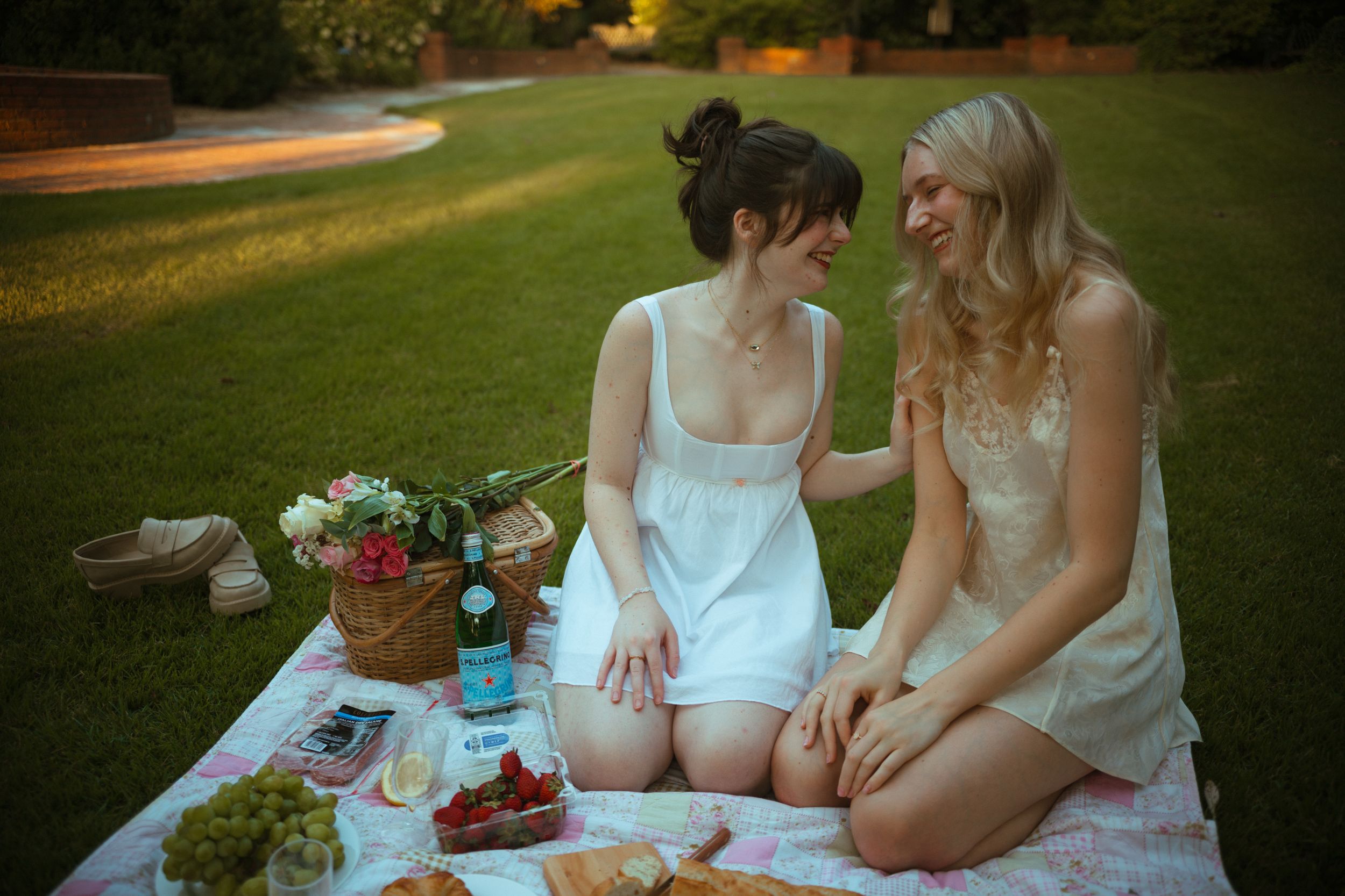 Two people share snacks and conversation during a summer garden picnic at sunset.