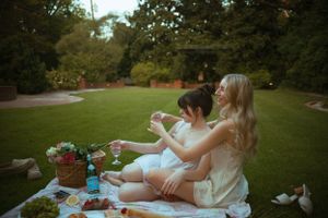 Friends share drinks during a summer evening picnic on a blanket.