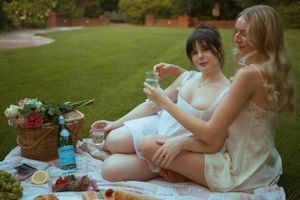 Friends share drinks and snacks during an intimate garden picnic.