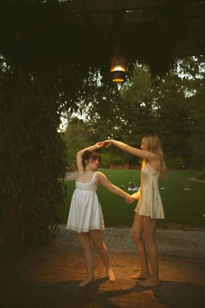 Two people dance under a hanging lantern at dusk in a garden setting.
