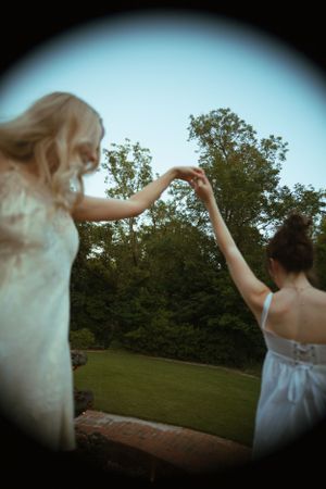 Two people dancing together create a circular frame against a blue sky and trees.